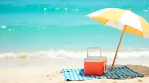Back to beach essentials image of an umbrella and cooler on the beach.